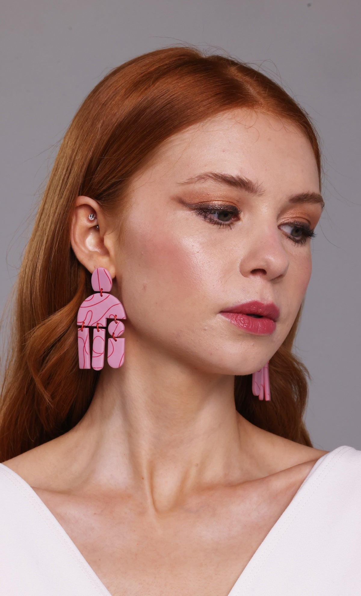 Woman wearing pink earrings with a neutral background