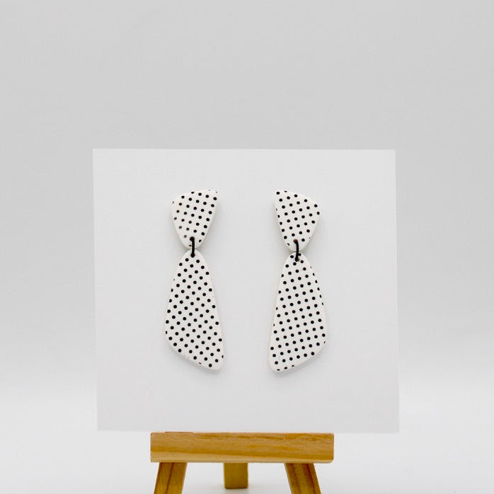 Polka dot patterned earrings on a white display card, with a bright white background.
